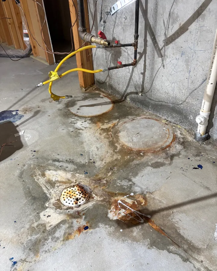 Before: a concrete floor with rust stains and construction residue around a drain.