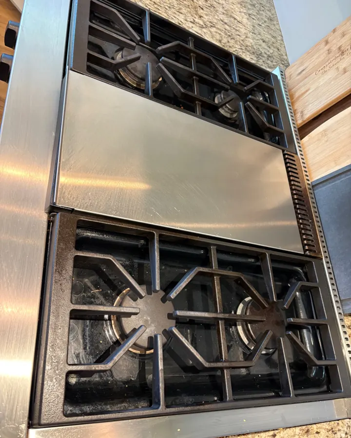 Before: a gas stove with crumbs and residue under the grates.