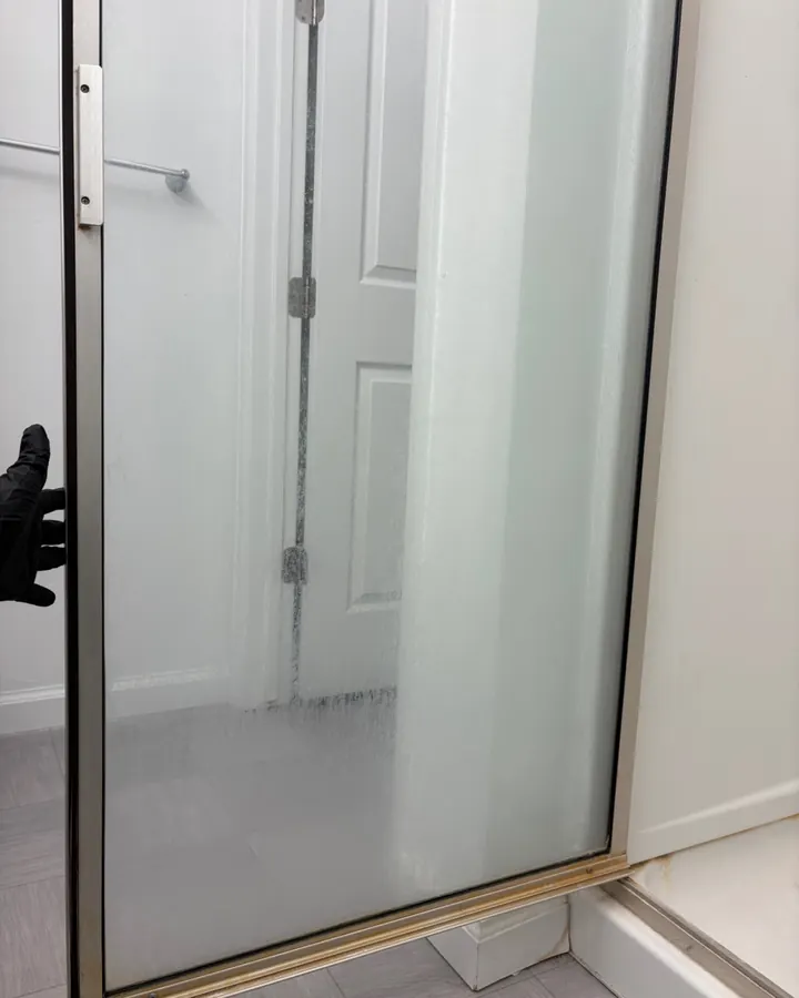 Before: a shower door clouded with haze and residue.