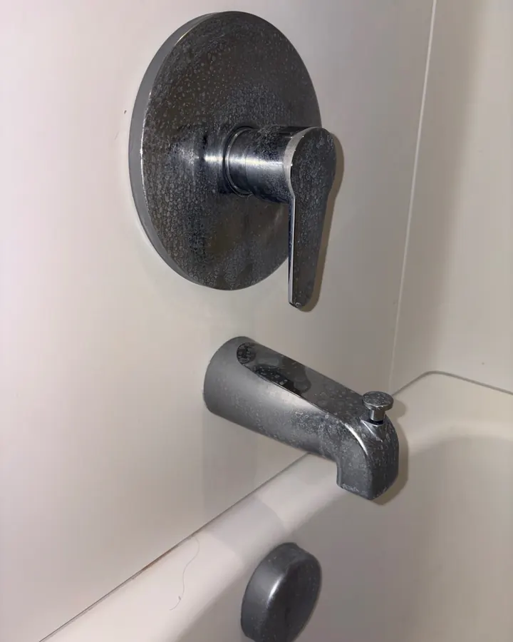 Before: a tub faucet and handle crusted with hard-water buildup.