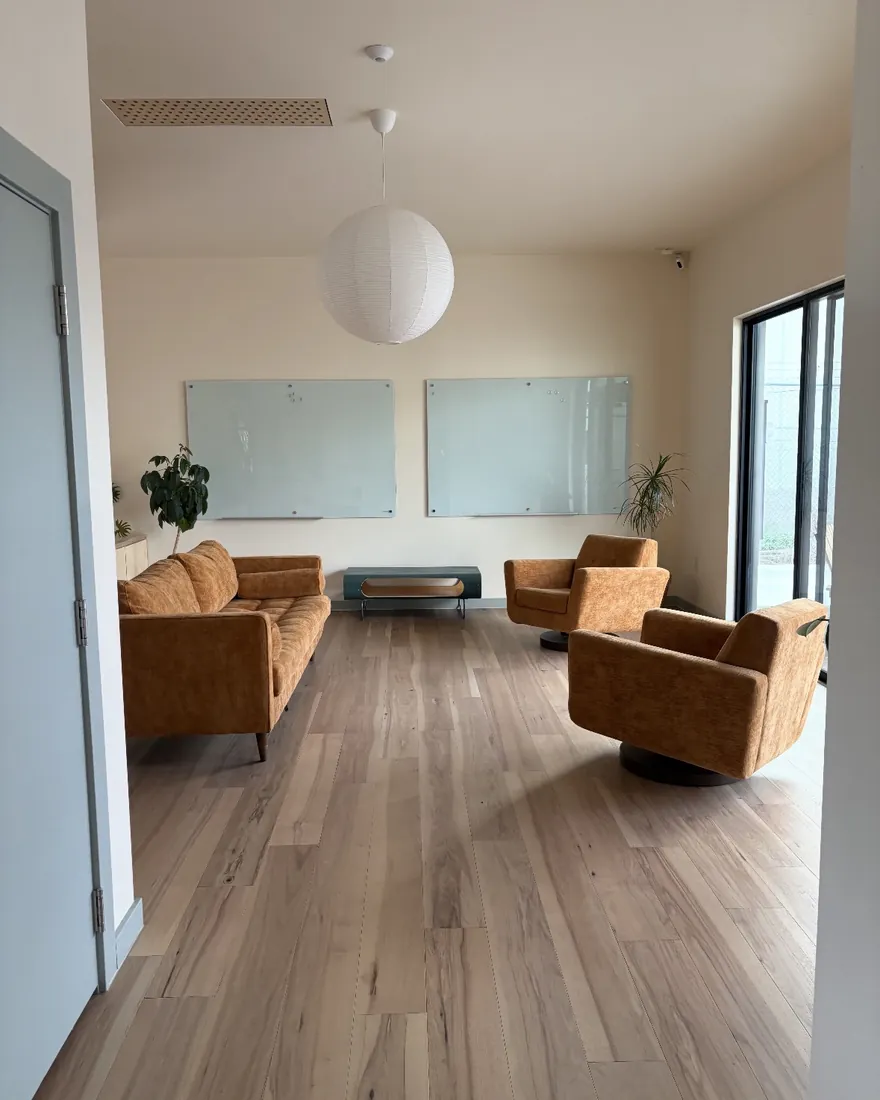 A lounge and meeting room with orange sofas, cleaned and ready for the day.
