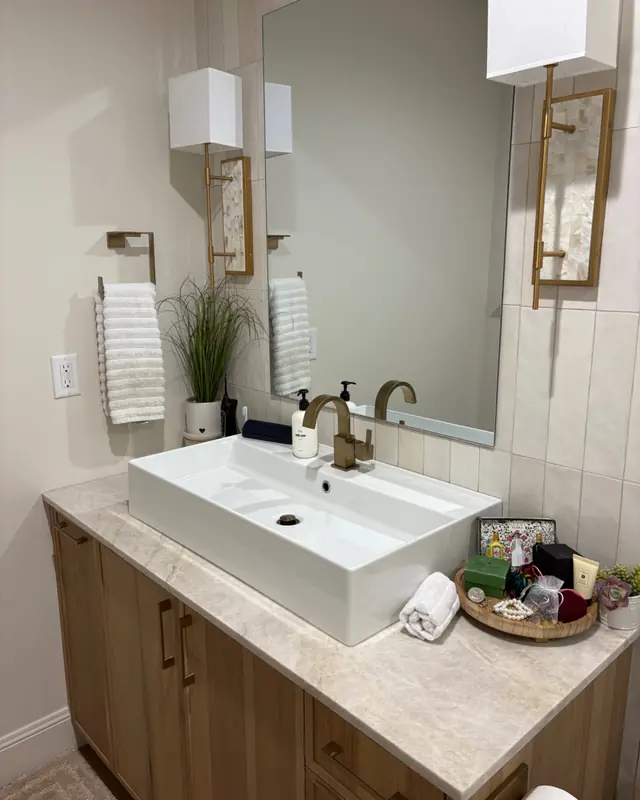 A bathroom vanity with a vessel sink, brass tap and folded towels.