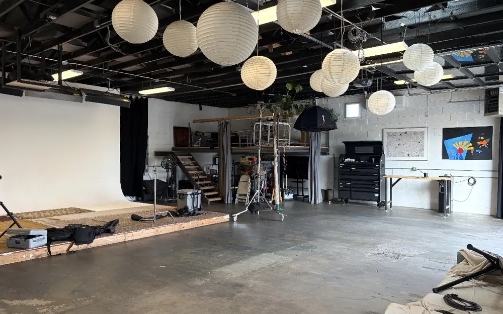A large photo studio with paper lanterns, a white backdrop and a swept concrete floor.