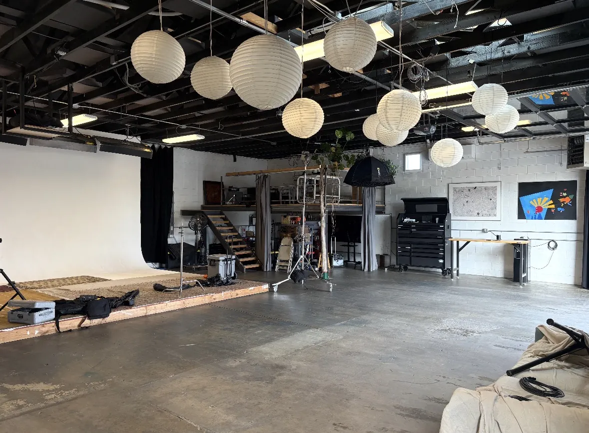A photo studio with paper lanterns overhead, floor swept and reset between shoots.